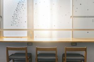 three chairs sitting under a counter with cabinets at Common de - Hostel & Bar in Fukuoka