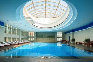 a large swimming pool in a building with a domed ceiling at Renaissance Tianjin TEDA Convention Centre Hotel in Binhai