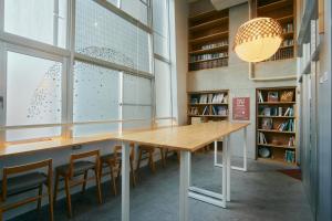 einen Tisch in einer Bibliothek mit Stühlen und einem großen Fenster in der Unterkunft Common de - Hostel & Bar in Fukuoka
