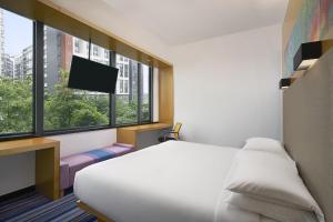 um quarto de hotel com uma cama e uma televisão em Aloft Guangzhou University Park em Guangzhou