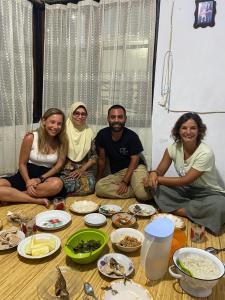 a group of people sitting on the floor with food at Ora Sunrise View in Negeri Saleman
