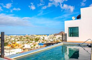 a swimming pool on the roof of a building with a city at Morgan Hotel Boutique & Residences, Los Cabos in Cabo San Lucas
