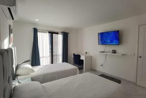 a hotel room with two beds and a tv at Morgan Hotel Boutique & Residences, Los Cabos in Cabo San Lucas