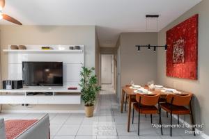ein Wohnzimmer mit einem Esstisch und einem TV in der Unterkunft 2 Quartos com Varanda a 300m RioCentro Wi-Fi 120mbps e Cozinha Completa - Condomínio com Piscina, Estacionamento, Portaria 24h e Parquinho Infantil - Apartamento indicado para Grupos, Hóspedes a Trabalho e Crianças in Rio de Janeiro