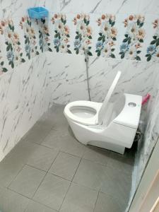 um WC branco numa casa de banho com flores na parede em Mutiara Dieng em Wonosobo