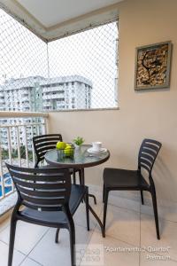 einen Tisch und Stühle in einem Zimmer mit Balkon in der Unterkunft 2 QUARTOS a 200m RIOCENTRO em CONDOMINIO com PISCINA, Estacionamento e Portaria 24h - Area de LAZER tambem para CRIANCAS - Wi-Fi 120mbps e Cozinha Completa in Rio de Janeiro