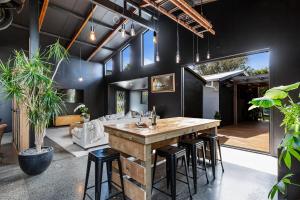 an open living room with a large wooden table and stools at The Black Barn in Auckland