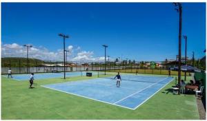 a group of people playing tennis on a tennis court at Apartamento Master VIP com 3 suítes noTree Bies Resort in Subaúma