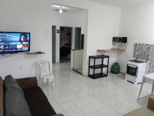 uma sala de estar com um sofá e uma televisão na parede em Espaço Mar Doce Lar - Praia Indaiá e Riviera em Bertioga