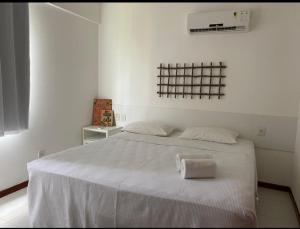 a bedroom with a white bed with a towel on it at Apartamento Térreo 3 suítes Master Resort Treebies à Beira Mar Subauma Bahia in Subaúma