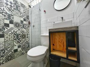 een badkamer met een toilet, een wastafel en een spiegel bij Casa hotel Los Laureles in Medellín