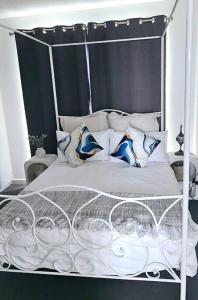 a white bed with a metal frame and pillows at San Remo Coastal Apartment in San Remo