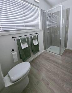 a bathroom with a toilet and a shower with towels at San Remo Coastal Apartment in San Remo