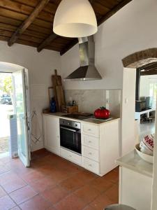 uma cozinha com armários brancos e um forno com placa de fogão em Fonte Freixo, em Borba, Alentejo em Borba