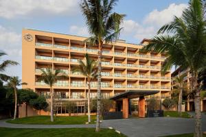 a large building with palm trees in front of it at Sheraton Maoming Romantic Beach Resort in Maoming