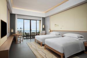 a hotel room with two beds and a television at Sheraton Maoming Romantic Beach Resort in Maoming