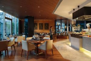 een restaurant met tafels en stoelen en een chef-kok die maaltijden bereidt bij Renaissance Beijing Wangfujing Hotel in Beijing