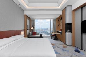 a bedroom with a large bed and a large window at Sheraton Guangzhou Panyu in Guangzhou