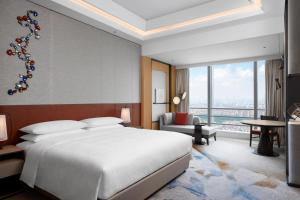 a bedroom with a large white bed and a large window at Sheraton Guangzhou Panyu in Guangzhou