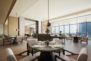 una sala da pranzo con tavoli, sedie e finestre di Liyang Marriott Hotel a Liyang
