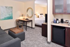 a hotel room with a bed and a desk with a mirror at SpringHill Suites by Marriott Corona Riverside in Corona