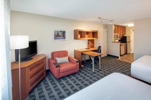 ein Hotelzimmer mit einem Schreibtisch, einem Stuhl und einem Zimmer in der Unterkunft TownePlace Suites by Marriott Bentonville Rogers in Bentonville