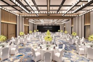 a ballroom with tables and white chairs and a projection screen at Courtyard by Marriott Nanjing Jiangning in Nanjing