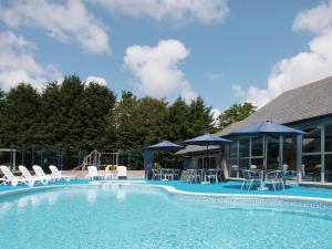 a swimming pool with chairs and umbrellas at Villa Gallery- 27073 in Perranwell