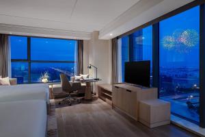 - une chambre avec un lit et un bureau avec une télévision dans l'établissement Shanghai Marriott Hotel Kangqiao, à Shanghai