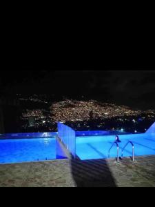 uma piscina à noite com uma cidade ao fundo em Hermoso apartamento en sector exclusivo. em Bello