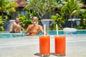 two drinks sitting on a table next to a swimming pool at ONAYA Bali Resort - Adults Only in Uluwatu