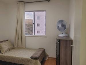 a bedroom with a bed and a window with a fan at Meu@Apê JF911 *Self-check-in*Elevador *Vaga grátis in Juiz de Fora