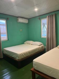 2 camas en una habitación con paredes y ventanas azules en Hostal Cay en Bastimentos