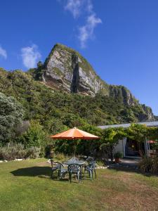 a table and chairs with an umbrella in the grass at Cliffscapes in Punakaiki