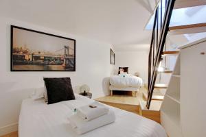 Un dormitorio con una cama blanca con una foto en la pared en Superbe duplex à proximité du Sacré Coeur!, en París