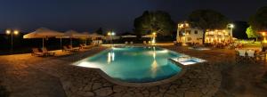 a swimming pool at night with chairs and umbrellas at Alexandros Hotel Apartments in Vourvourou