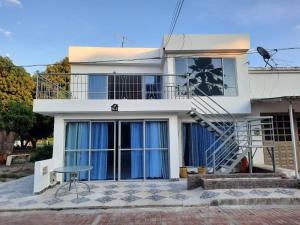 a white house with a balcony and a stool at CASA VACACIONAL Babilonia in Girardot