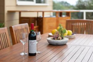 Ourania Luxury Villa with unforgettable sea views في راي: زجاجة من النبيذ موضوعة على طاولة خشبية مع كأسين من النبيذ