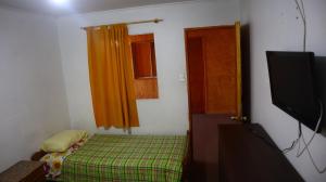 a small room with a bed and a flat screen tv at Residencial familiar El Valle in Calama