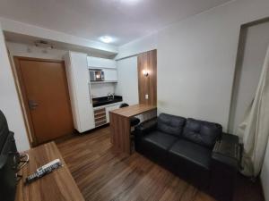 a living room with a black couch and a kitchen at 511. Flat Hotel S4 in Brasilia