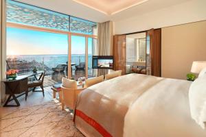 a bedroom with a large bed and a large window at Bulgari Resort, Dubai in Dubai