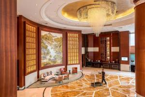 a lobby with a chandelier and a person standing in the middle at Courtyard by Marriott Shanghai Fengxian in Fengxian