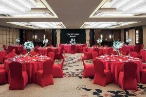 una sala conferenze con tavoli e sedie rossi e un palco di Courtyard by Marriott Shanghai Changfeng Park a Shanghai