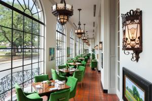 un ristorante con sedie verdi, tavoli e finestre di The St. Anthony, a Luxury Collection Hotel, San Antonio a San Antonio