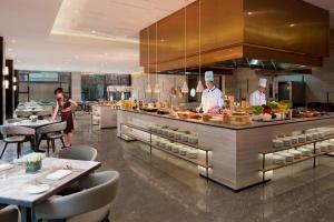 a restaurant with two chefs preparing food in a kitchen at Courtyard by Marriott Shanghai Fengxian in Fengxian