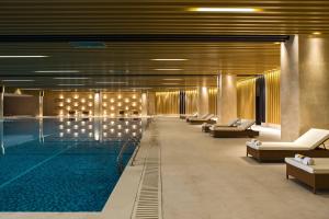 einen Pool mit einer Reihe von Liegestühlen und einem Pool in der Unterkunft Renaissance Nanjing Olympic Centre Hotel in Nanjing