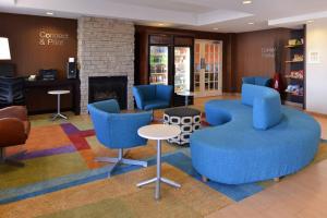 a waiting room with blue chairs and a fireplace at Fairfield Inn and Suites by Marriott Dayton Troy in Troy