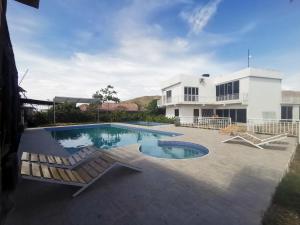 uma piscina com duas espreguiçadeiras e uma casa em QUINTA RANCHO SANTIAGO CAMPESTRE capacidad 50 huéspedes em Yaguará