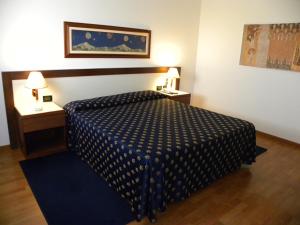 um quarto com uma cama com um edredão azul e branco em Arcotel em Villanova Monferrato