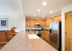 a kitchen with a stainless steel refrigerator and wooden cabinets at Bear Creek Lodge 208A by Alpine Lodging Telluride in Telluride